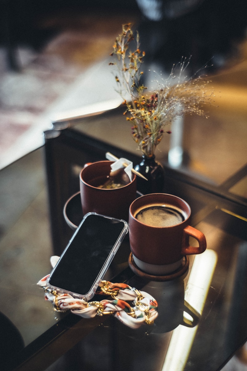 a table with a couple of mugs and a cell phone